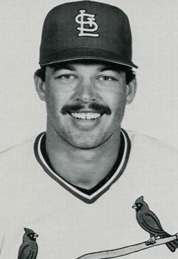 black and white photo of man in baseball jersey and cap with logo StL